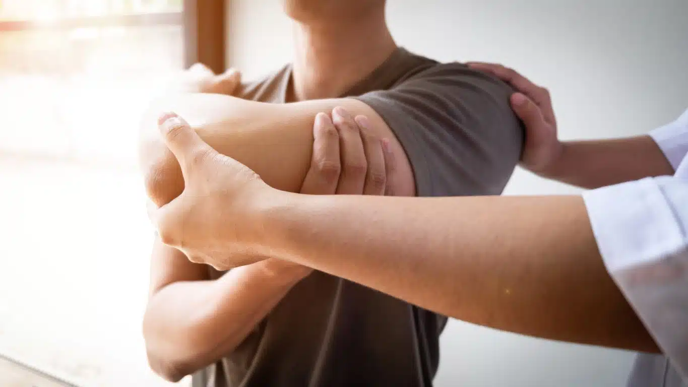 Therapist Treating A Male Injured By Rotator Cuff Stretching